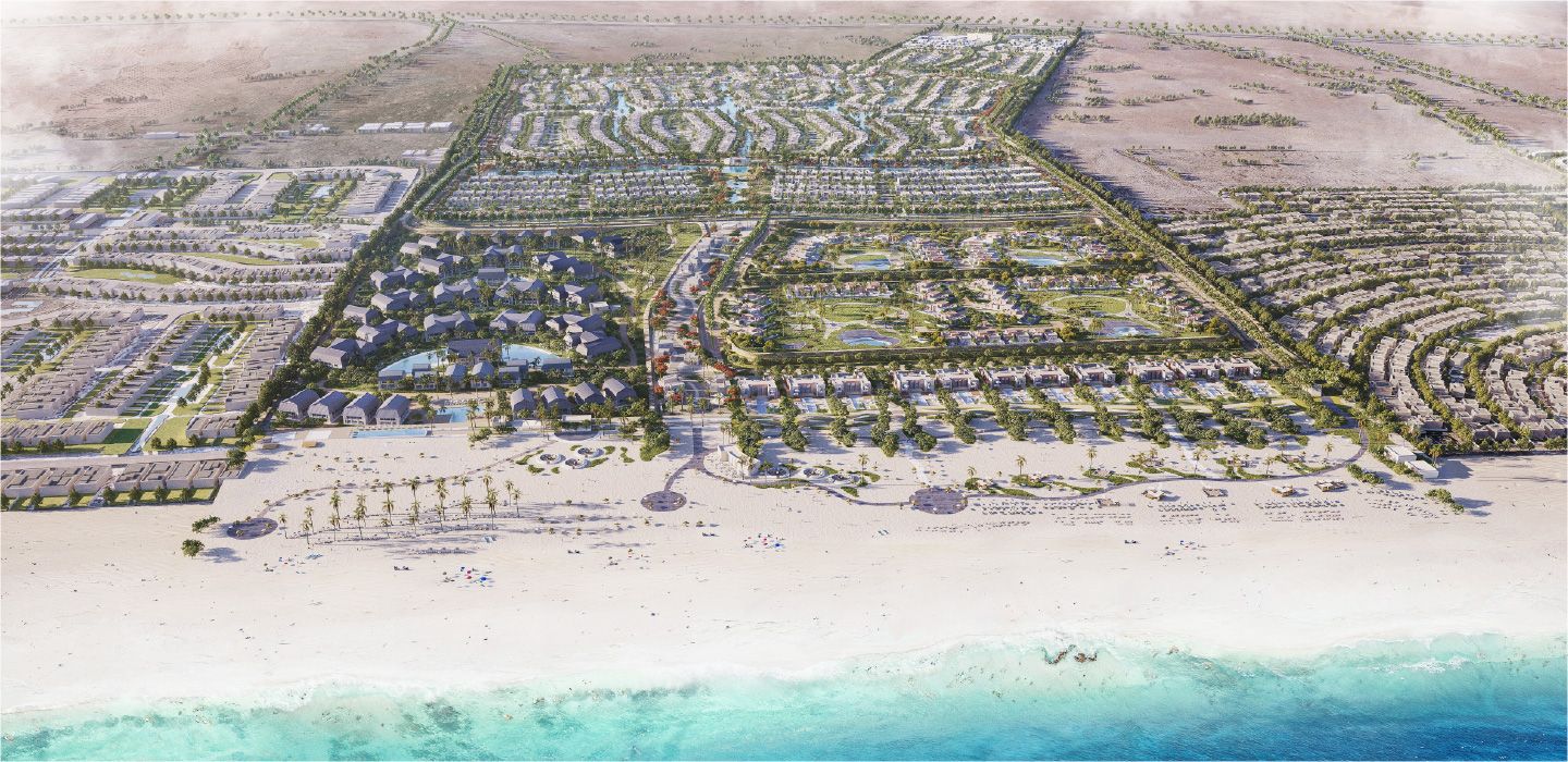 Unlabeled oblique aerial masterplan rendering showing beach in foreground, residential clusters, roads, pools/lagoons and planted areas inland. It is an architectural rendering rather than flat surveyed cartography.